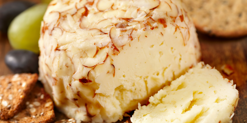 Cheese ball coated in sliced almonds served with crackers and grapes