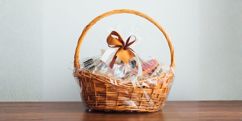 Wicker gift basket wrapped in clear cellophane with ribbon bow
